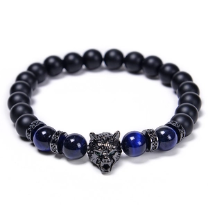 Detailed shot of tiger eye beads and matte black beads with a zircon wolf head charm