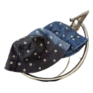 Three colors of denim bucket hats with daisy embroidery displayed on a curved metal stand