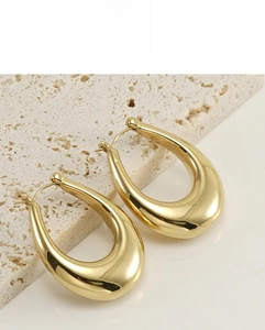 Detail of 18K gold-plated teardrop earrings with a high-polished metallic finish