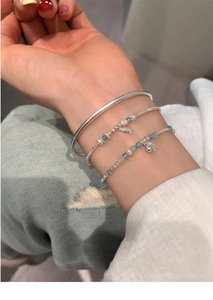 Detail view of ethnic style beaded fish bracelet with pearls and silver bangle on wrist
