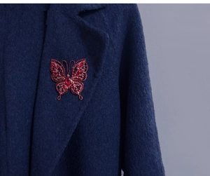 Détail d'une broche papillon vintage avec gemmes rouges sur le revers d'un manteau