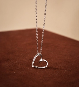 Macro detail of 925 sterling silver hollow heart pendant on a fine cross chain