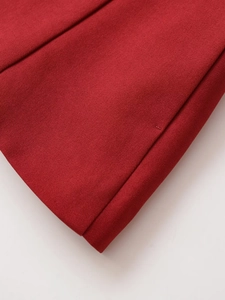 Detailed close-up of red twill fabric texture and stitching on a belted vest top