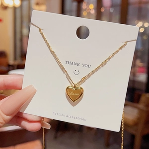 Detailed close-up of golden heart pendant featuring Love engraving and a delicate chain
