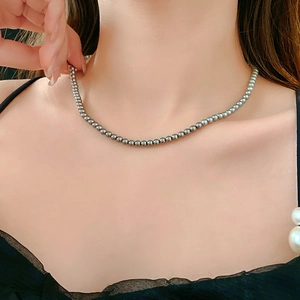 Close-up of minimalist silver-gray pearl necklace worn on model neck for fit and luster