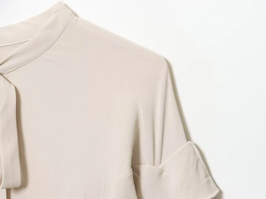 Close-up of beige round neck blouse showing textured chiffon fabric and sleeve details