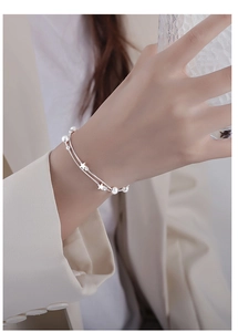 Close-up of double-layer silver star bracelet with beads on a woman's wrist