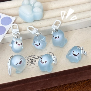 Close-up of six translucent light blue ghost keychains with cute expressions on a tray