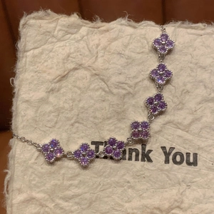Macro shot of silver bracelet with sparkling purple zircon clover charms on paper