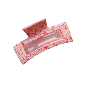 Pink matte acrylic square hair claw clip with red splatter pattern on white background