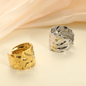 Detail of wide gold and silver stainless steel rings with irregular hammered texture on silk