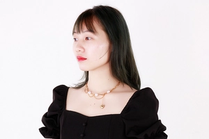 Gros plan d'un collier multicouche doré avec perles baroques et pendentif coeur sur modèle