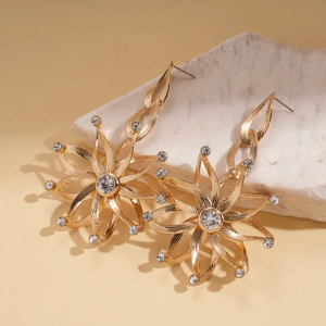 Elegant gold flower drop earrings with sparkling rhinestones on a white stone base