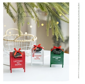 Three festive Christmas mailboxes in red, white and green with mini wreaths on a tabletop
