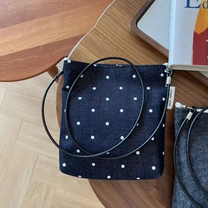 Detail of blue polka dot denim crossbody bag with zipper and Simple Wish side label
