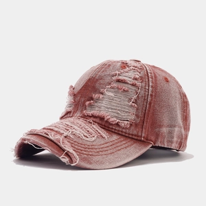 Vintage distressed baseball cap in washed rust red with large holes and frayed edges