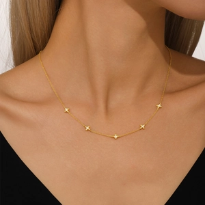 Close-up of a gold choker necklace with five dainty diamond-studded cross charms on a model