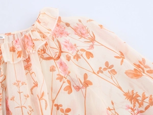 Detailaufnahme des Rüschenausschnitts und Blumendrucks der Chiffon-Bluse