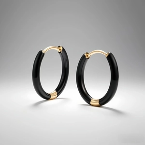 Close-up of black enamel hoop earrings with polished gold-tone metal accents and high-end texture