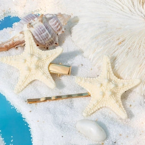 Ocean style starfish hair clips set on white sand with sea shells for beach vacation