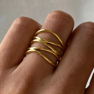 Macro shot of gold-plated multi-layered twisted open ring on model's finger