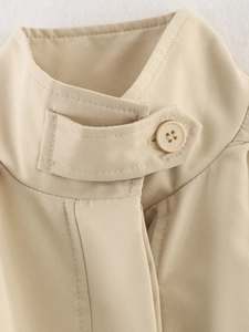 Macro detail of khaki jacket featuring high neck collar with resin button and strap