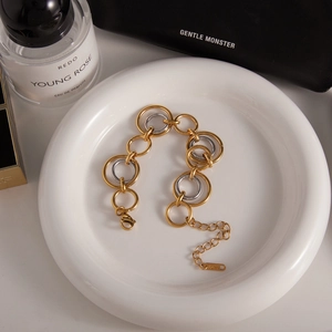 Two-tone stainless steel link bracelet in gold and silver finish displayed in a dish