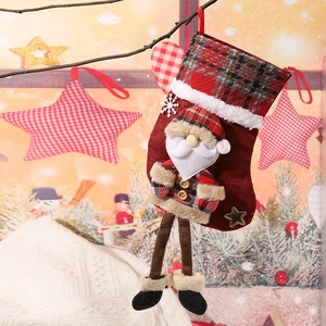 Detail of red and brown plaid Christmas stocking featuring a 3D Santa doll with hanging legs