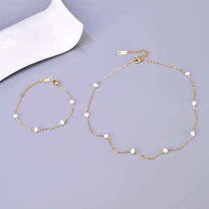 Detailed top view of gold chain jewelry set with freshwater pearls on purple background