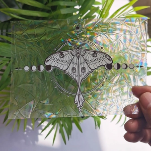 Handheld suncatcher sticker featuring a moth and moon phases with rainbow prism effect