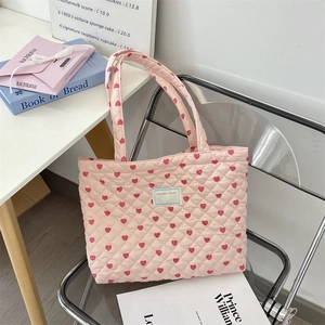 Close-up of pink quilted tote bag with red heart patterns and Sezakka Studio label
