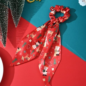 Detailed view of red Christmas fabric scrunchie with festive Santa and reindeer patterns