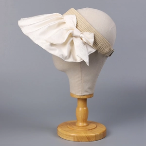 Detail of light yellow straw sun visor with cream satin bow and metal adjustable buckle