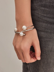 Close-up of a silver C-shaped open bangle featuring three elegant freshwater pearls