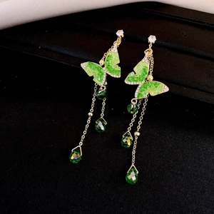 Detail of green butterfly drop earrings with cubic zirconia and long metal tassels