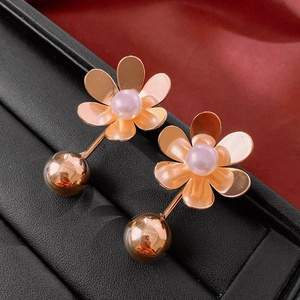 Detailed view of rose gold flower earrings with a pink pearl on black leather case