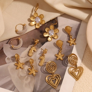 Detailed flat lay of 18K gold plated starfish, shell, and heart earrings on silk fabric