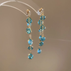 Dettaglio di orecchini lunghi a frangia placcati oro 18k con perline di vetro blu