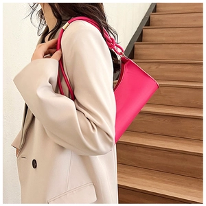 Close-up of vibrant rose red baguette bag with knotted shoulder strap detail