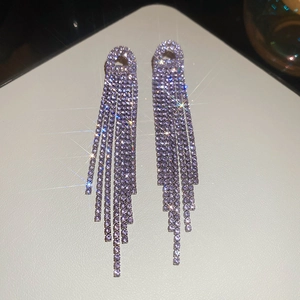 Macro detail of elegant long tassel earrings with sparkling rhinestones and starburst light