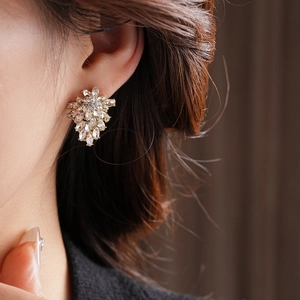 Detailed close-up of a gold flower stud earring with sparkling marquise-cut crystals