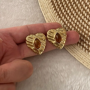 Vintage gold heart stud earrings with amber stone and wrinkled texture on a white backdrop