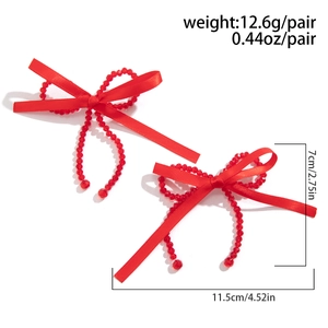 Detail view of red ribbon bow earrings with beads and crystal tassels on white background