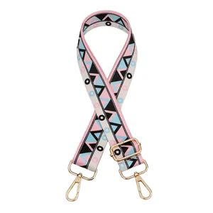 Detail of adjustable woven bag strap with pink and blue geometric patterns and gold hooks