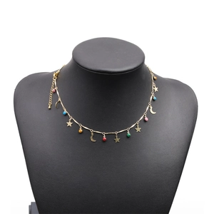 Detail of gold star and moon charms with colorful beads on a black velvet necklace display
