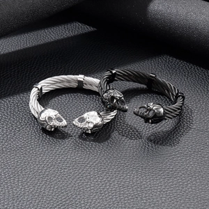 Detail of silver and black punk skull cable bracelets on textured leather background