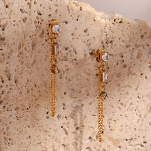 Golden tassel drop earrings with sparkling zircon stones on a textured stone background