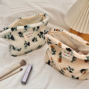 Detail of plush lamb wool makeup bags with colorful floral patterns and metal zipper