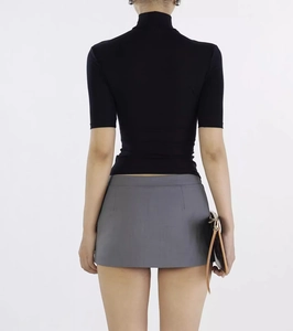Rear view of a slim-fit black high-neck knit top paired with a gray mini skirt