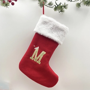 Detail of red knit Christmas stocking featuring a gold letter M with a small Santa hat